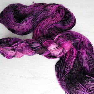 May include: A skein of purple and black yarn with a gradient of colour. The yarn is soft and fluffy, and it would be perfect for knitting or crocheting.