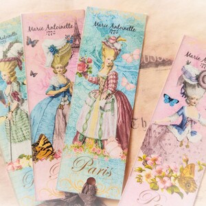 May include: Four pink and blue bookmarks with a vintage design featuring a woman in a dress and a large hat. The bookmarks have the text "Marie Antoinette" and "Paris" on them.