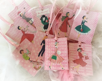 May include: Pink gift tags with a vintage Christmas theme featuring women in various holiday outfits. The tags have different designs with text that says "Tis the season" and "Be Merry!"