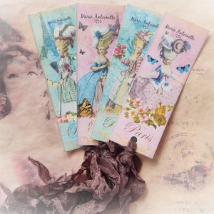 May include: Four vintage bookmarks with a Parisian theme. Each bookmark features a woman in a dress with a large hat, a butterfly, and the text "Marie Antoinette 1776" and "Paris".