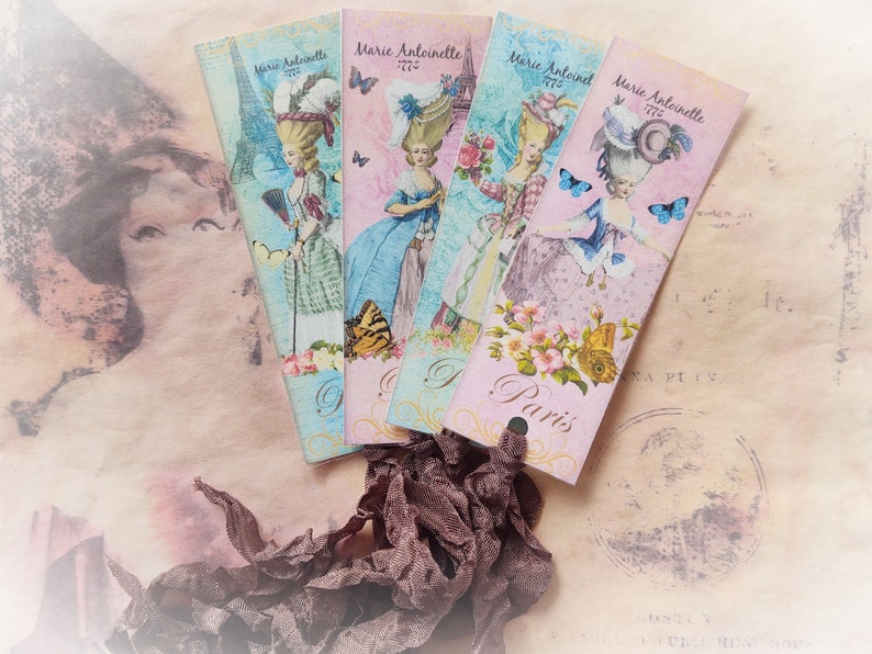 May include: Four vintage bookmarks with a Parisian theme. Each bookmark features a woman in a dress with a large hat, a butterfly, and the text "Marie Antoinette 1776" and "Paris".