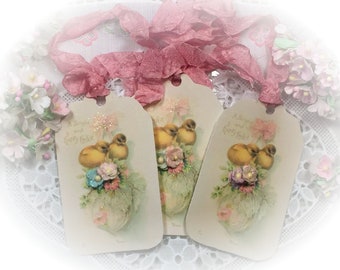 May include: Three white gift tags with a pastel pink and blue floral design and a picture of two yellow chicks in a nest. The tags have the text "A Bright and Happy Easter" printed on them.