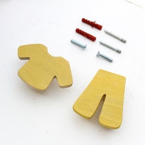 May include: Two yellow wooden cabinet pulls with a unique shape, alongside red and silver screws and anchors. The pulls have a light wood grain and are set against a white background, suggesting a DIY or home improvement theme.