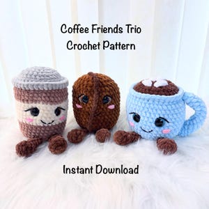 Op de afbeelding: Drie gehaakte knuffelfiguren met het label Coffee Friends Trio Crochet Pattern en Instant Download. De figuren bestaan uit een bruine en crèmekleurige koffiebeker, een donkerbruine koffieboon en een lichtblauwe mok met witte marshmallows, allemaal met zwarte ogen.