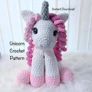 May include: A handmade crochet unicorn in white and pink, with a gray horn and blue eyes. The text "Unicorn Crochet Pattern" is displayed on the left side of the image, with "Instant Download" at the top.
