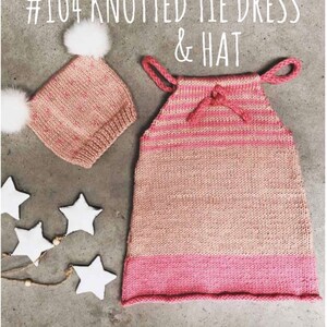 May include: A knitted baby dress and hat set in shades of pink and beige. The dress features a tie detail at the shoulders and a contrasting pink band at the bottom. The hat has two white pom-poms. Text on the image reads: #104 KNOTTED TIE DRESS & HAT.