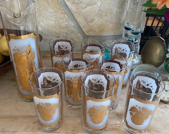May include: Set of nine vintage gold and white glasses with a fruit design. The glasses are tall and slender with a rounded base. The design features a gold fruit motif on a white background. The glasses are perfect for serving juice, water, or cocktails.