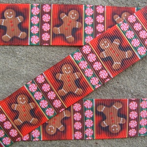 May include: Red and white ribbon with a repeating pattern of gingerbread men and candy canes. The gingerbread men are brown and have white icing and smiling faces.