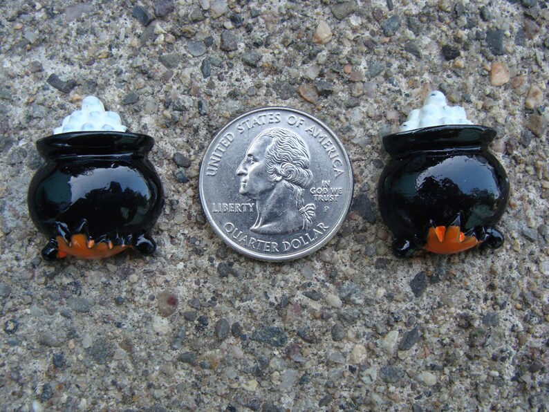 Puede incluir: Dos adornos de Halloween de caldero negro con espuma blanca en la parte superior. Los calderos son aproximadamente del tama&ntilde;o de una moneda de 25 centavos de d&oacute;lar estadounidense.