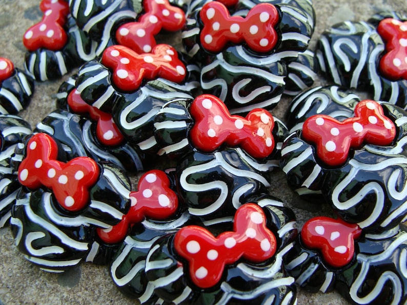 Puede incluir: Una colecci&oacute;n de botones rayados en blanco y negro con lazos rojos de lunares. Los botones est&aacute;n hechos de un material brillante y tienen un efecto 3D.