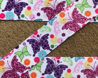 May include: White ribbon with a repeating pattern of colorful butterflies and flowers. The butterflies are purple, pink, and green.