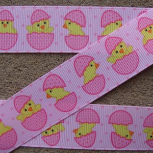May include: Pink ribbon with a repeating pattern of yellow chicks hatching from pink eggs. The eggs have a white polka dot pattern.