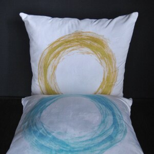 May include: Two white throw pillows with abstract circle designs. The top pillow has a yellow circle design and the bottom pillow has a blue circle design.