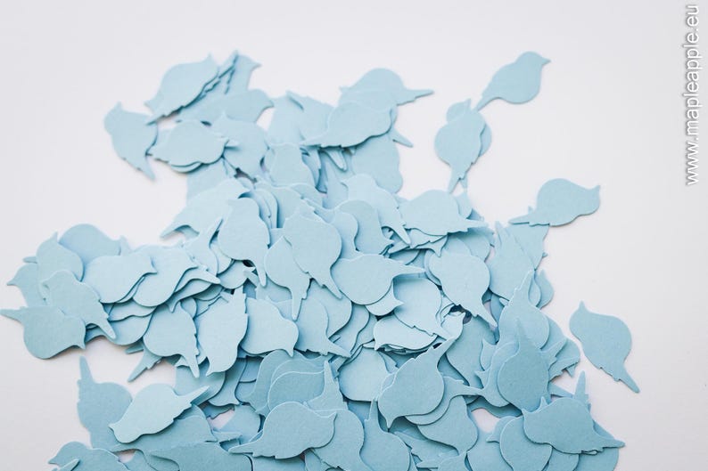 May include: A collection of pale blue bird-shaped paper cutouts. The cutouts are arranged on a white background, creating a decorative effect. The shapes are consistent, suggesting they are for crafting or embellishment purposes.
