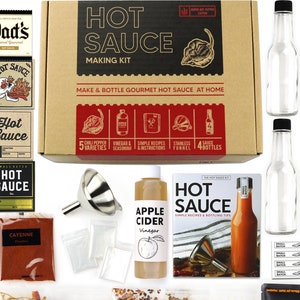 May include: A hot sauce making kit with a cardboard box, glass bottles, and various ingredients. The kit includes labels, a funnel, vinegar, and different chili pepper varieties. The box reads "Hot Sauce Making Kit."