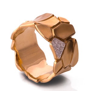May include: A gold ring with a textured, geometric design. The ring has a single row of small diamonds set in the center.