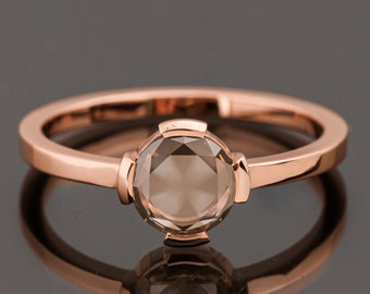 Op de afbeelding: Een ring van roségoud met een ronde, gefacetteerde, bruine edelsteen.