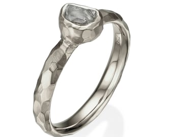 May include: A silver ring with a hammered texture and a clear, faceted gemstone set in the center.
