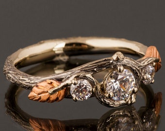 Puede incluir: Un delicado anillo de plata con un diseño de rama y tres diamantes redondos. El anillo presenta dos pequeñas hojas de oro rosa.