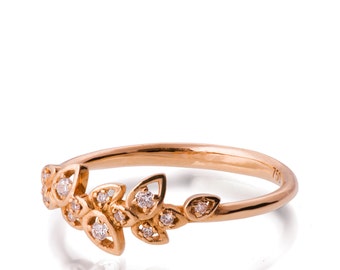 May include: A delicate gold ring with a floral design featuring small diamonds. The ring is made of 18 karat gold and has a polished finish.