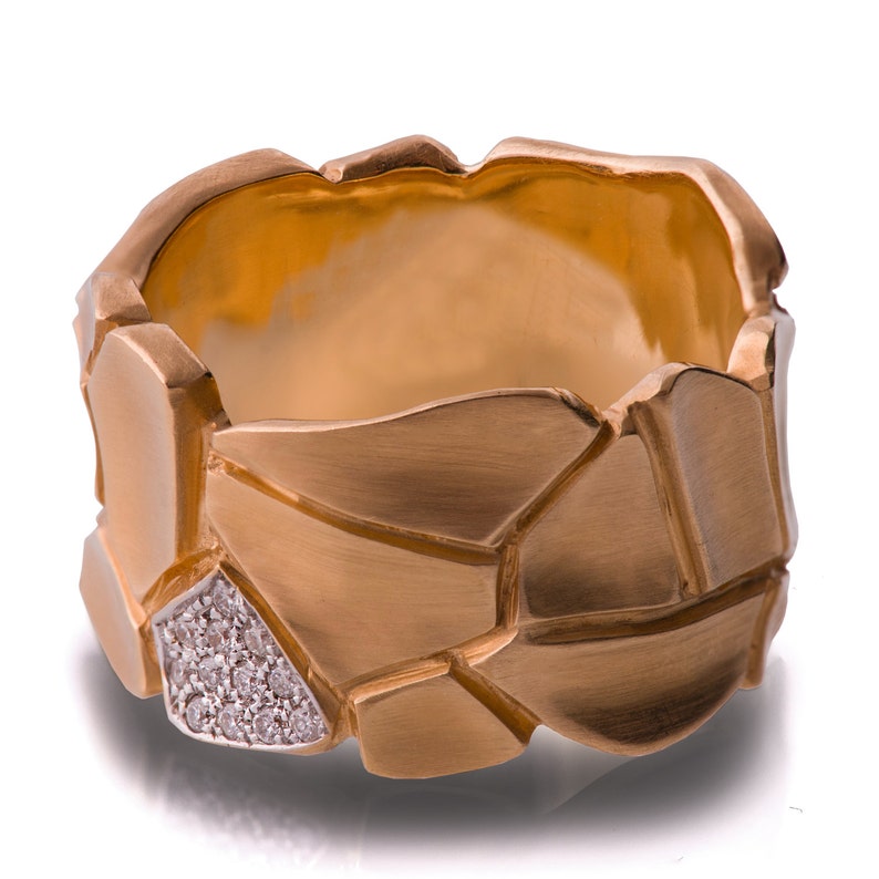 May include: A gold ring with a textured, geometric design. The ring is set with small diamonds.