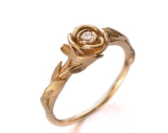 May include: A gold ring with a rose design and a small diamond in the center.