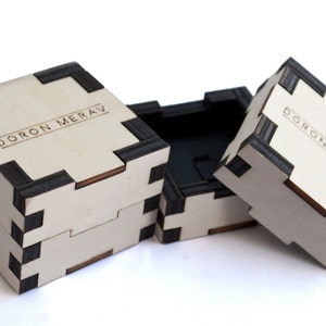 May include: Three wooden boxes with black trim and the text "DORON MERAV" engraved on the top. The boxes are stacked on top of each other.