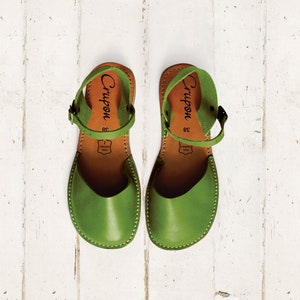 Op de afbeelding: Een paar groene leren sandalen met enkelbandjes. De sandalen hebben een bruine leren zool en de merknaam "Crupon" staat op de bandjes.