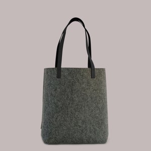 May include: A gray felt tote bag with black leather handles.