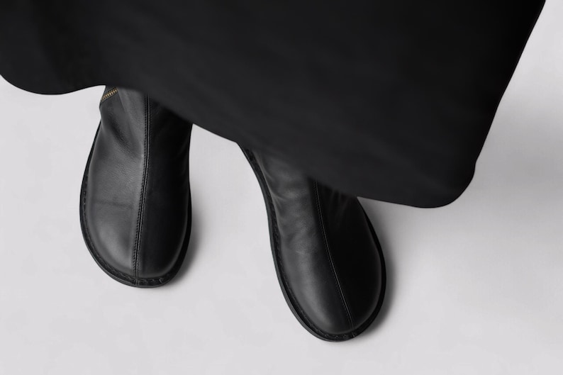 Pu&ograve; includere: Un paio di stivaletti in pelle nera con punta a punta e cerniera laterale.