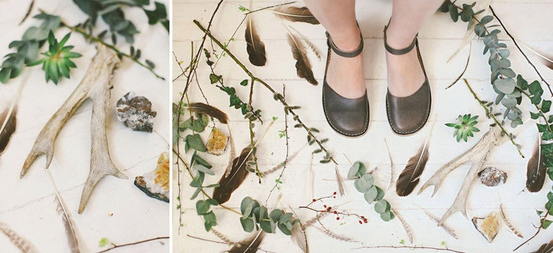 May include: A pair of brown leather ankle strap sandals with a white background featuring antlers, feathers, and greenery.