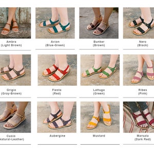 May include: Twelve pairs of women's sandals in various colors, including brown, blue-green, black, gray-brown, red, green, pink, natural leather, purple, yellow, and dark red. The sandals are all flat and have a simple design.