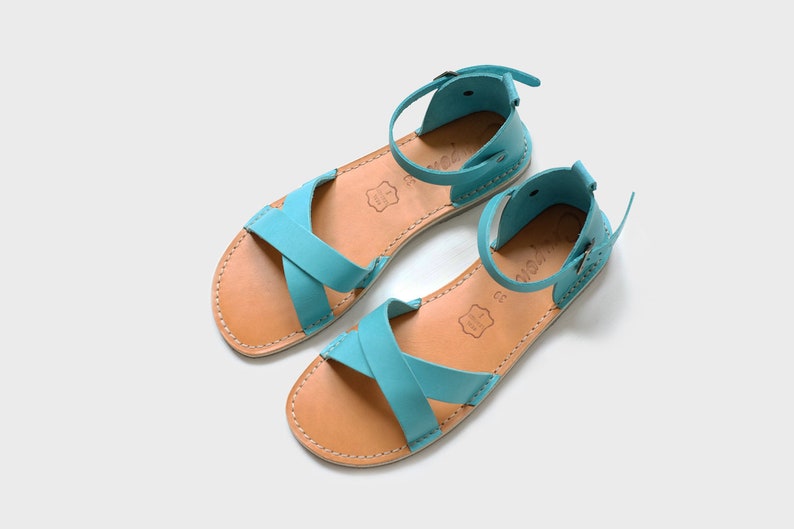 May include: A pair of turquoise leather sandals with ankle straps and brown leather soles.