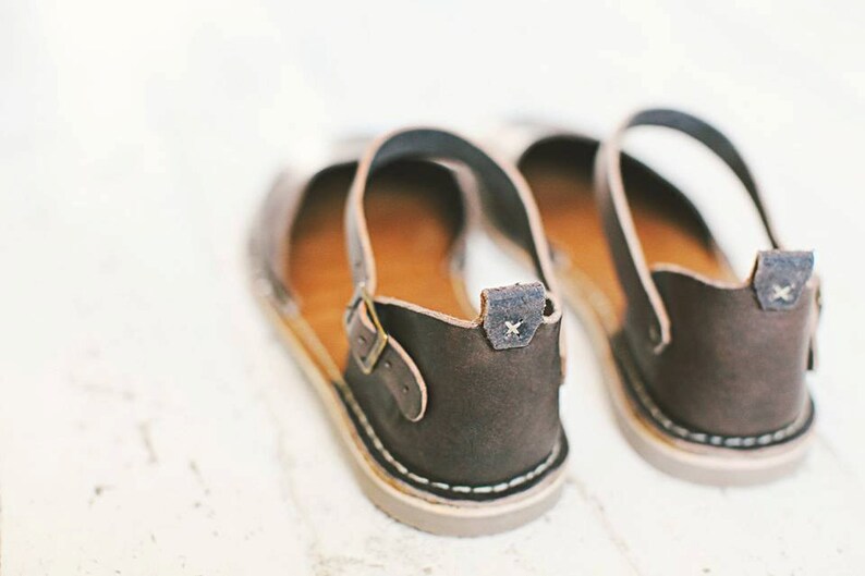 May include: A pair of brown leather sandals with adjustable straps and a buckle closure. The sandals have a simple design and are made of high-quality leather.