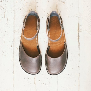 May include: A pair of brown leather sandals with ankle straps. The sandals have a simple design and are made of a soft, supple leather.
