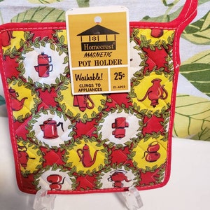 May include: Red and yellow quilted pot holder with a green leaf design. The pot holder has a magnetic backing and is washable. The text on the tag reads "Homecrest Magnetic Pot Holder Washable! Clings to Appliances 25c E1-A923"