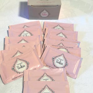 May include: A collection of pink packets and a box labeled "Finger Pinkies Secretary's Hand Cleaner." The packets and box feature a floral design around the words "Pinkies."