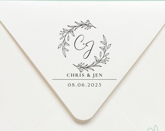 Könnte beinhalten: Ein weißer Umschlag mit einem schwarz-weißen Hochzeitsstempel. Der Stempel zeigt einen floralen Kranz mit den Initialen "C+J" und dem Text "CHRIS & JEN 08.06.2023".