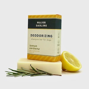 May include: A bar of dog shampoo with the text "MAJOR DARLING DEODORIZING shampoo bar for dogs lemon verbena". The bar is next to a lemon wedge and a sprig of rosemary.