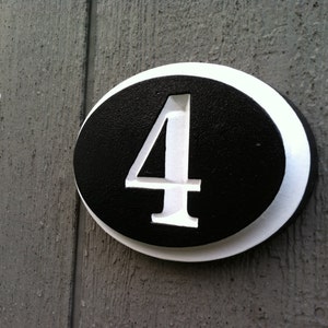 May include: A white oval-shaped house number sign with a black background and the number "4" in white.