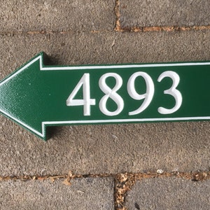 May include: Green arrow-shaped house number sign with white trim and the number 4893 in white.
