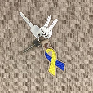 May include: A yellow and blue ribbon keychain with a set of keys attached. The ribbon is a symbol of awareness for Down syndrome.
