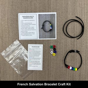 May include: French Salvation Bracelet Craft Kit with instructions, beads, and black cord. The kit includes a small bag of beads, a black cord, and instructions in French for making a bracelet.