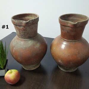 May include: Two brown clay jugs with a wide base and a narrow neck. The jugs are labeled #1 and #2.