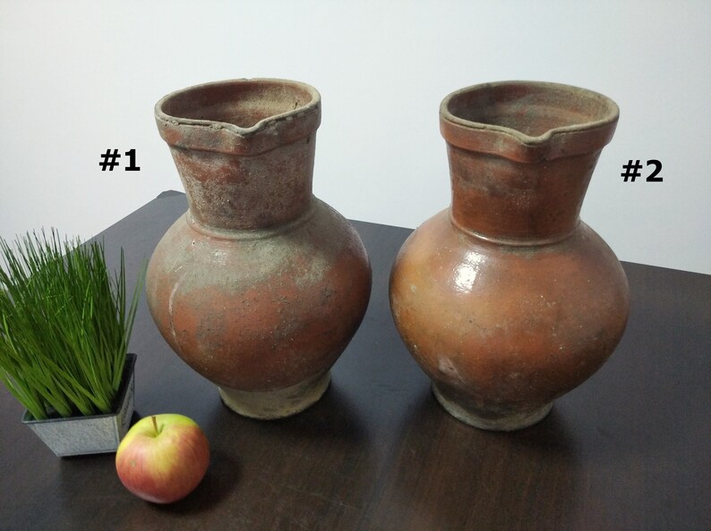 May include: Two brown clay jugs with a wide base and a narrow neck. The jugs are labeled #1 and #2.
