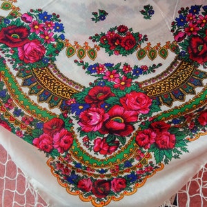 K&ouml;nnte beinhalten: Ein wei&szlig;er Stola aus Stoff mit einem bunten Blumenmuster. Das Muster zeigt rote, rosa, blaue und gr&uuml;ne Blumen mit goldenen Akzenten. Der Stola hat einen Fransenrand.