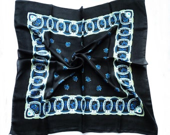 Könnte beinhalten: Ein schwarzes Bandana mit einem weißen und blauen Blumenmuster. Das Bandana hat einen Fransenrand und ist in der Hälfte gefaltet.