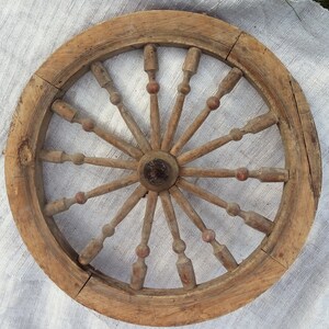 May include: A wooden wheel with spokes radiating from the center. The wheel is made of natural wood and has a rustic appearance.