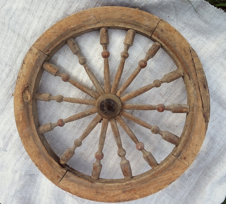 May include: A wooden wheel with spokes radiating from the center. The wheel is made of natural wood and has a rustic appearance.