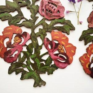 Peut inclure: Deux motifs floraux en bois sculpt&eacute;s de mani&egrave;re complexe, peints dans des tons de rouge, rose et vert. Les fleurs ont un design d&eacute;coup&eacute; et sont peintes dans un style rustique et vintage.